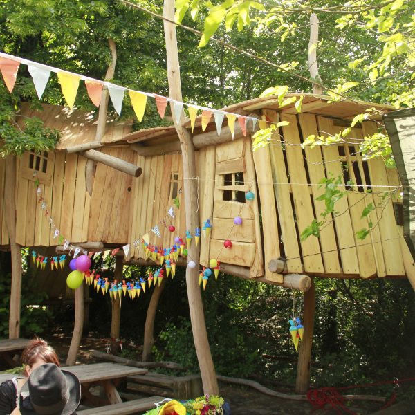 Ein Kinder-Baumhaus, geschmückt mit bunten Wimpelketten