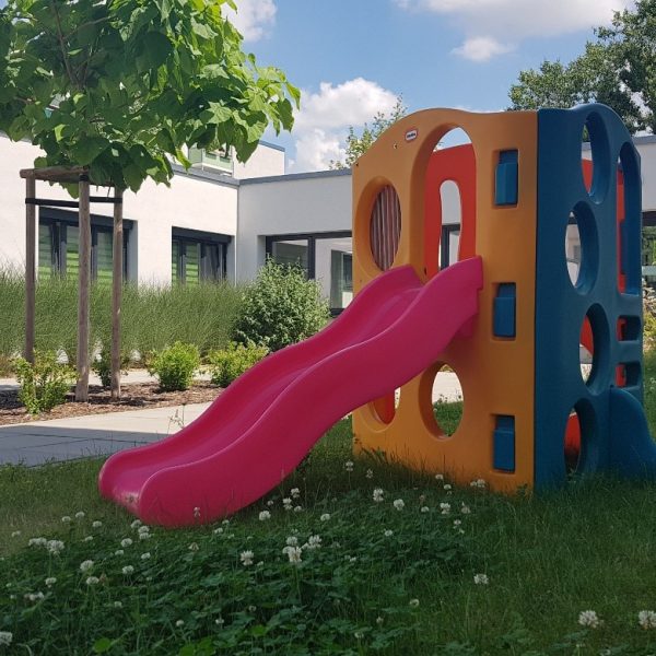 Im Garten steht ein Kinder-Kletterturm mit Rutsche.