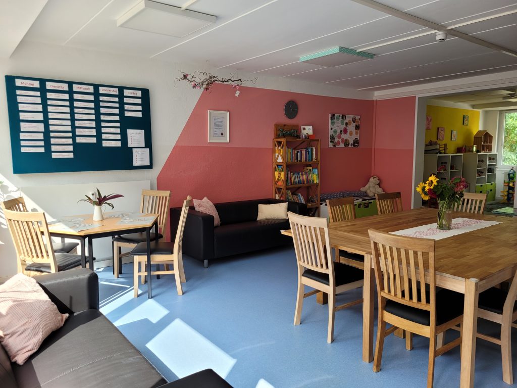 Im offenen Treff des Familienzentrums Thekla stehen ein großer Tisch mit Stühlen und gemütliche Sofas.