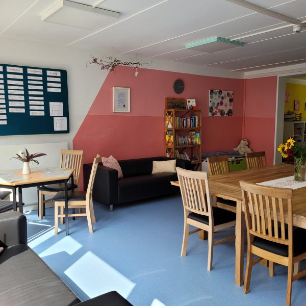 Im offenen Treff des Familienzentrums Thekla stehen ein großer Tisch mit Stühlen und gemütliche Sofas.