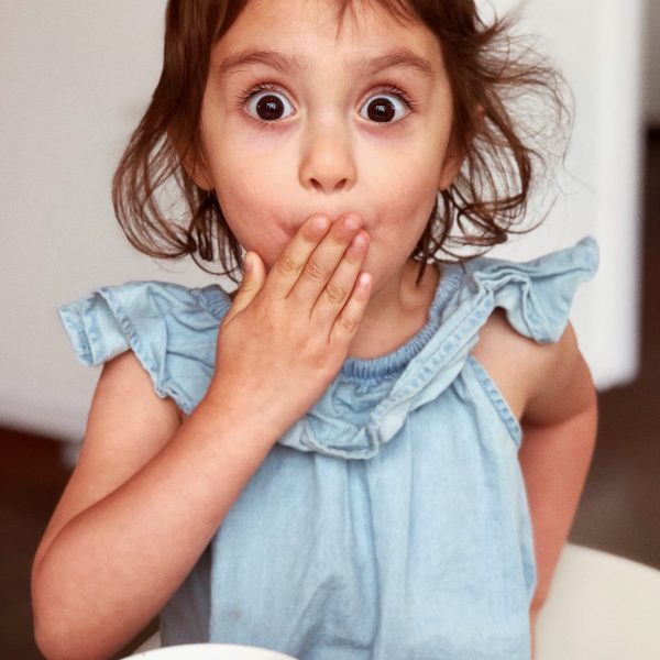 Ein Kind hält sich die Hand vor dem Mund und schaut erstaunt.