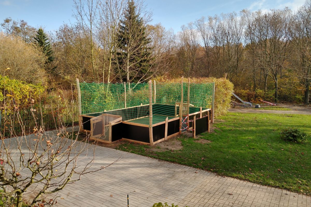 Im Garten des Kindergartens steht ein Fußballfeld mit Banden.