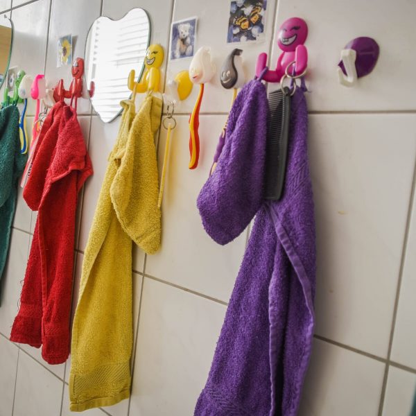 Bunte Handtücher hängen an Fliesen im Badezimmer.