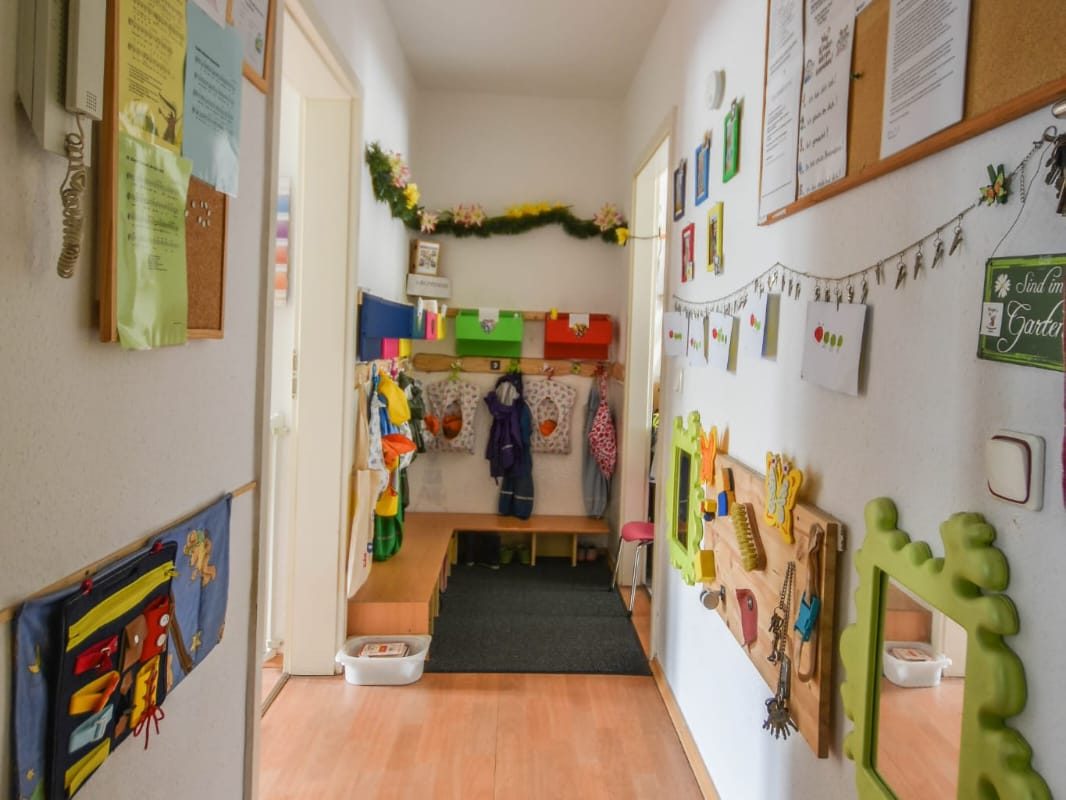 Flur mit Kindergarderobe und vielen Activity-Boards an der Wand.