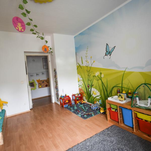 Buntes Kinderzimmer mit Spielzeug und Kuschelecke.
