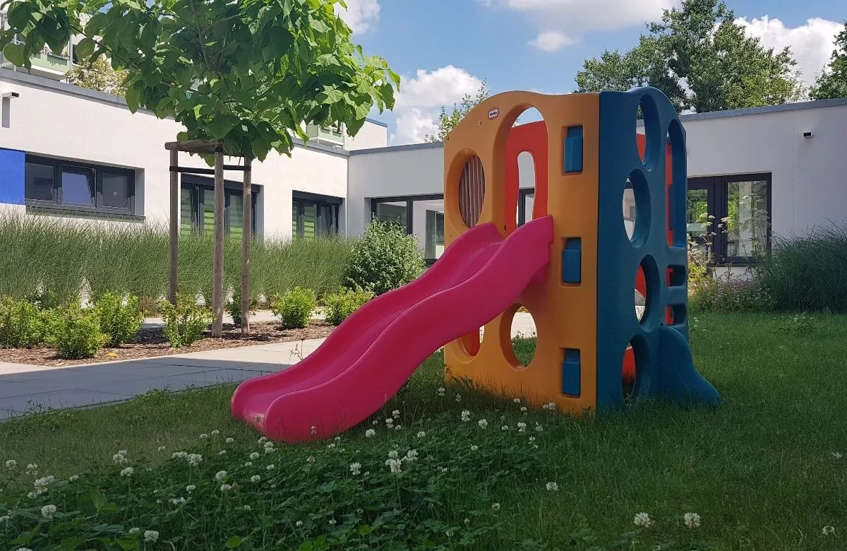 Im Garten steht ein Kinder-Kletterturm mit Rutsche.