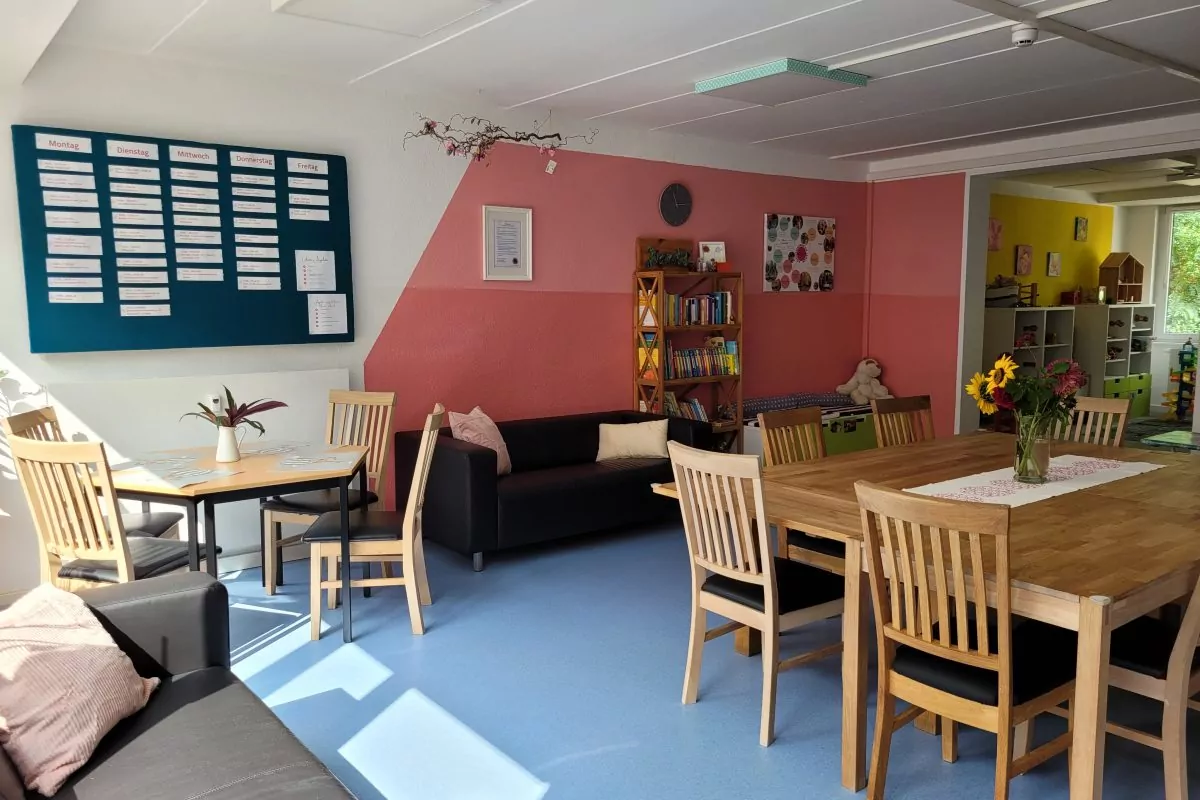 Im offenen Treff des Familienzentrums Thekla stehen ein großer Tisch mit Stühlen und gemütliche Sofas.