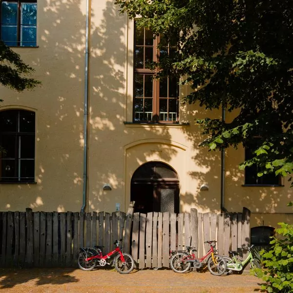 Eingang zur Kita "Treffpunkt Linde", dieser wird von einem Zaun mit Kinder-Fahrrädern leicht verdeckt.