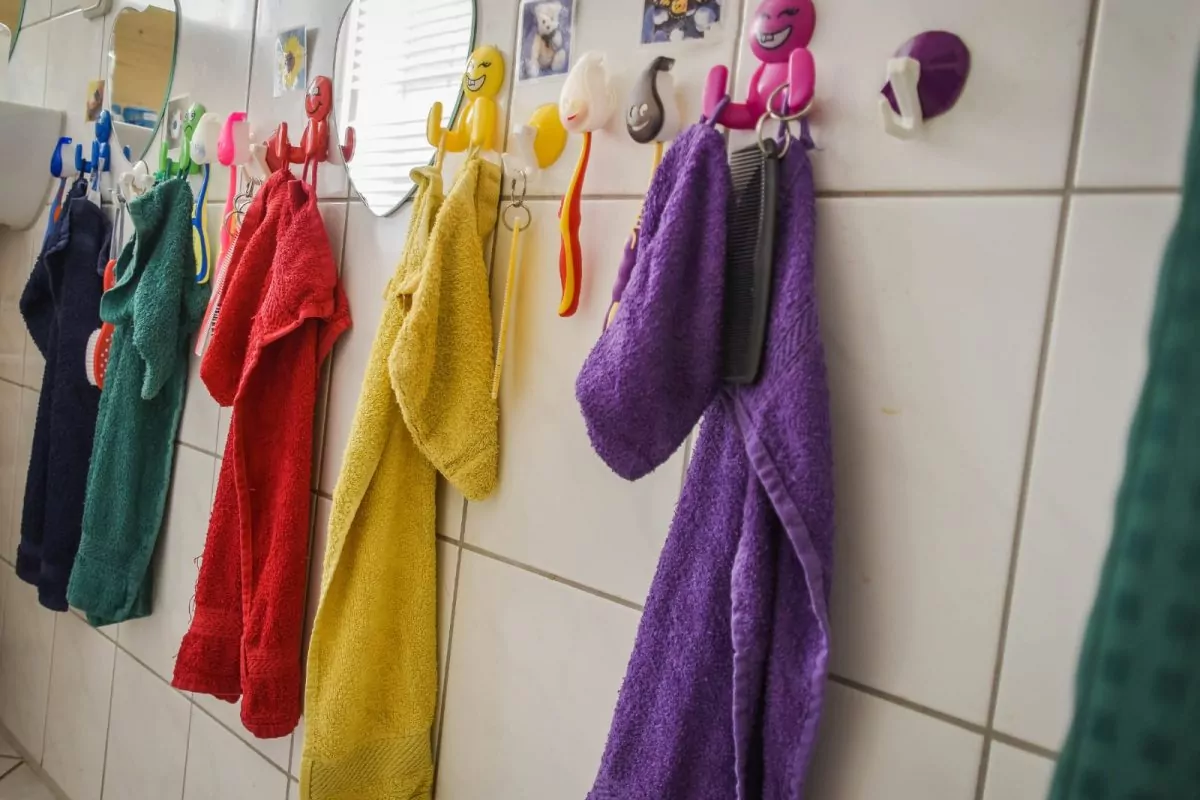 Bunte Handtücher hängen an Fliesen im Badezimmer.