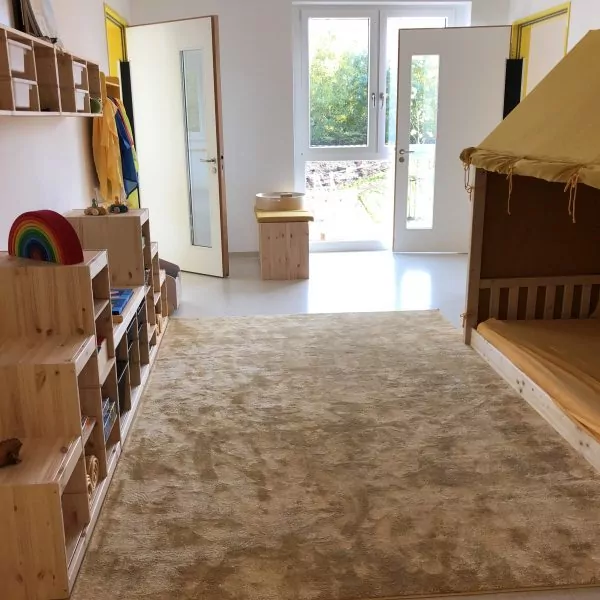 Ein heller Raum mit Kinder-Kuschelecke und Regalen mit Spielzeug.