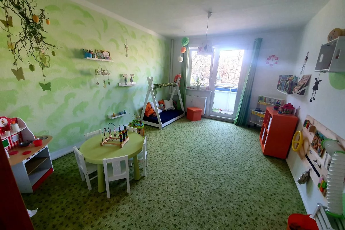 Ein großes Kinderzimmer in den Farben grün, orange und weiß gestaltet.