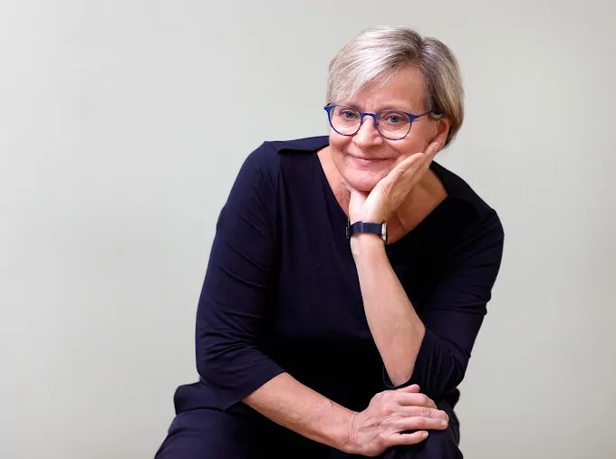 Wir begrüßen Hebamme Raja Rohrwacher im Familienzentrum Paunsdorf - FiZ Leipzig Eine Portraitaufnahme der Hebamme Raja Rohrwacher, die freundlich in die Kamera lächelt. Sie trägt kurzes graues Haar, ein dunkles Kleid und eine Brille mit dunklem Rahmen.