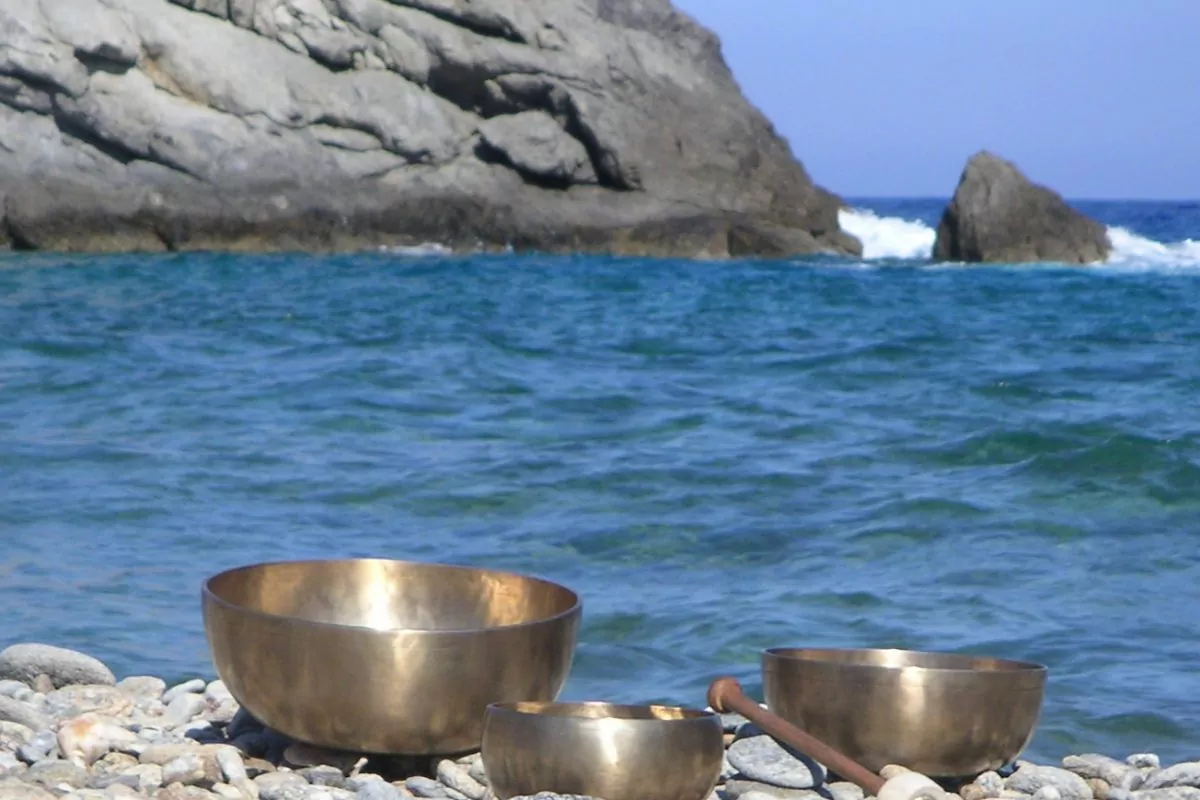 Ein Bild mit 3 Klangschalen an einem Steinstrand vor dem Meer.